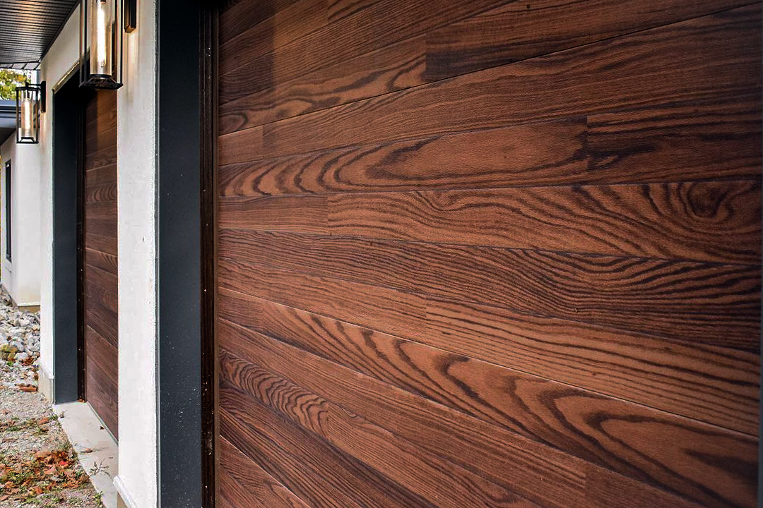 planks garage door in faux woodtone dark oak close up image on white exterior with black trim